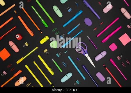 Creative pattern made of neon colorful stationery set on black background. Stock Photo