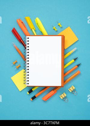 Empty notebook page with space for your text with yellow, red and orange stationery on blue background. Flatly. Stock Photo