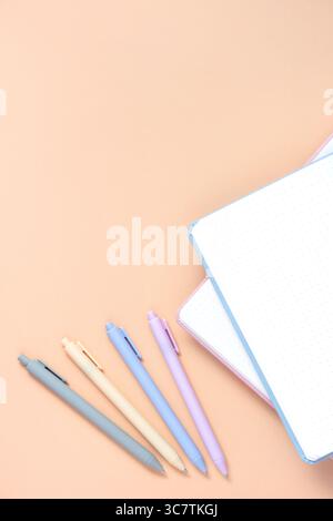 Top view of part of a notepad sheet and pastel colors ball-point pens over light yellow background with copy space. Minimalist flat lay composition as Stock Photo