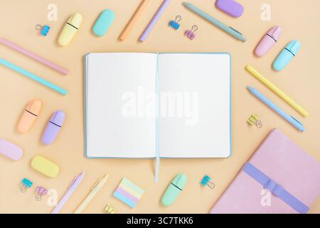 Open notebook with space for your text with pastel color school and office stationery on yellow background. Flatly. Stock Photo