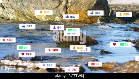 Digital notification icons hovering over rocky shoreline at water's edge, combining nature and tech Stock Photo