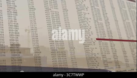 Displaying flight board showing codes and times on glass panel at airport, with building reflection Stock Photo