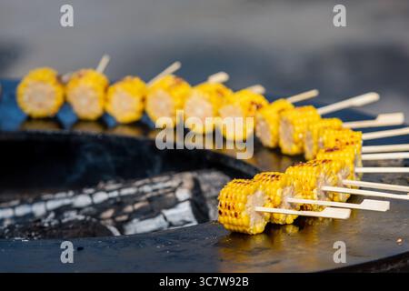 Grilled corn on the cob skewers arranged in a circle on a barbecue grill. Juicy golden kernels roasted over an open flame, perfect for summer BBQ Stock Photo