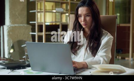 Asian businesswoman girl Korean business woman female office manager boring online work typing laptop computer tired exhausted Chinese Japanese worker Stock Photo