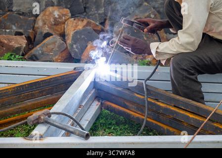Indian worker doing welding. Close-up Metal worker welding iron in a workshop Stock Photo