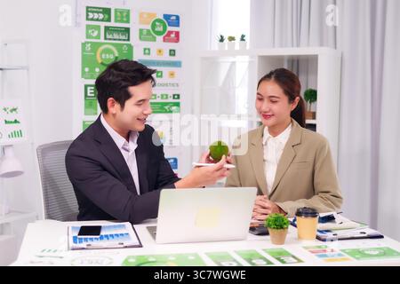 Two Asian colleagues collaborate on environmental social governance goals exploring sustainable business practices in a professional setting Stock Photo