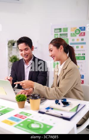 Asian business professionals collaborate on laptop discussing project strategy in modern office for innovative solutions Stock Photo