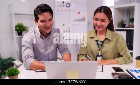 Adult Asian colleagues in modern office engaged in productive collaboration digital work analyzing data for business success professional teamwork hap Stock Photo