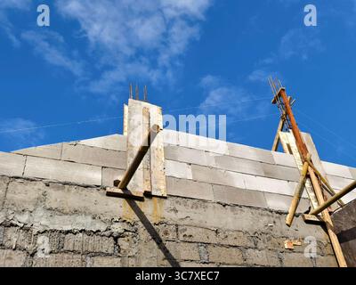 Reinforced concrete columns and lightweight brick wall under construction using steel rebar and alignment string Stock Photo