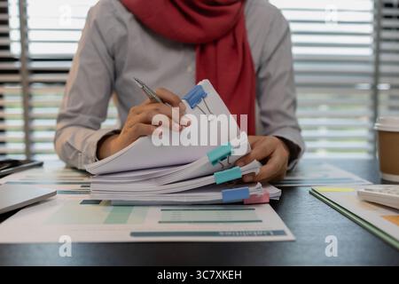 a muslim company employee works in a large financial organization, a muslim female entrepreneur is reviewing her company's financial documents, market Stock Photo