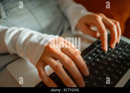 Female hands typing on laptop keyboard, working remotely from home office, coding and developing project, representing digital freelance workplace with professional productivity Stock Photo