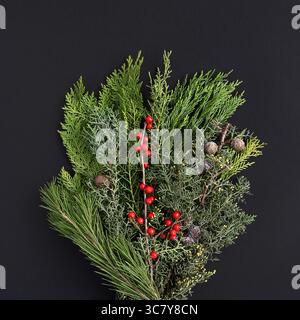 Winter bouquet of thuja, juniper and berries on a dark background Stock Photo