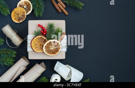 Craft gift box with dried oranges, spruce branches and berries on gray background. Gift wrapping. Space for your text Stock Photo