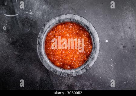 Exquisite salmon roe, vibrant and rich, ideal for adding a touch of elegance to your culinary creations. black background. top view. Stock Photo