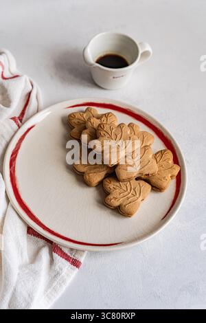 Close-up of a plate of traditional Canadian maple leaf shaped cookies with a jug of maple syrup Stock Photo