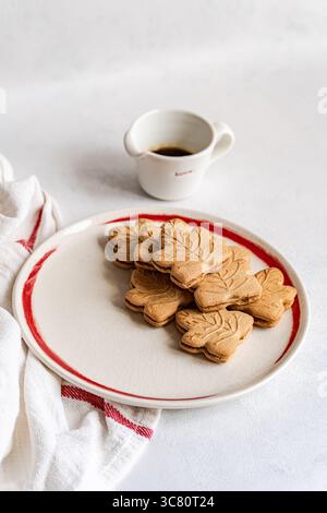 Close-up of a plate of traditional Canadian maple leaf shaped cookies with a jug of maple syrup Stock Photo