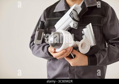 Unrecognizable male technician in uniform holding cctv security camera and going to install it Stock Photo