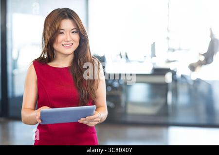 Digital tablet resting on glass desk in modern office workspace, featuring bright natural light Stock Photo