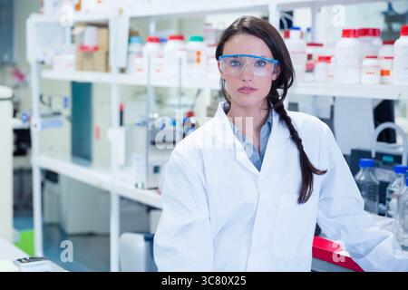 Reagent bottles with red green blue caps are sitting on white bench in laboratory beside glassware Stock Photo