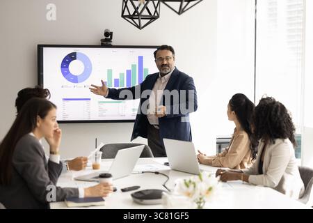 Mature business leader present statistic on screen to young managers Stock Photo
