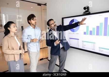Mature businessman mentor teach diverse young interns at digital board Stock Photo
