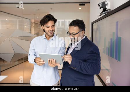 Young worker explain successful solution to smiling leader using tablet Stock Photo