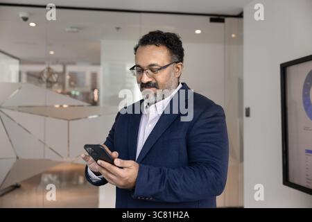 Mature businessman senior executive text messages using app on cell Stock Photo