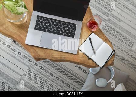 Modern home office setup featuring laptop, plants, and notebook on a wooden table, ideal for remote work and freelance lifestyle Stock Photo