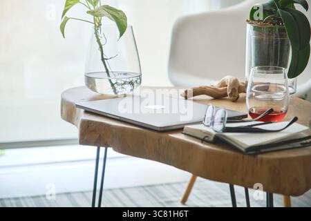 Modern home office setup featuring laptop, plants, and notebook on a wooden table, ideal for remote work and freelance lifestyle Stock Photo