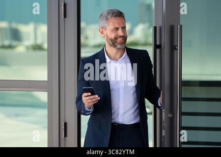 Business man entering an office building. Mature businessman walking into a meeting. Business man stepping through an office door. Charismatic Stock Photo