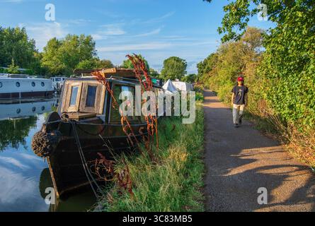 Young man listening to headphones while enjoying a walk on a canal towpath, Lee Valley canal towpath, London, England, UK. Stock Photo