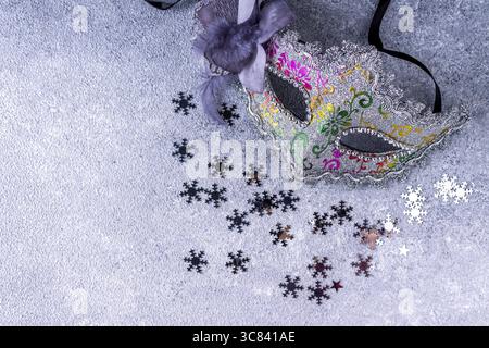 Christmas mask made of silver paper, confetti on gray background close up Stock Photo