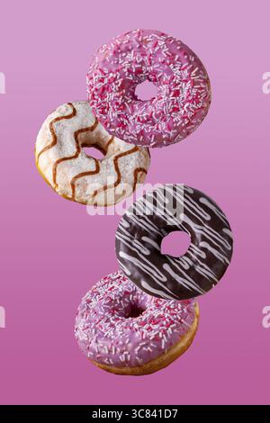 Donuts in chocolate and in sugar glaze fly on a pink background Stock Photo