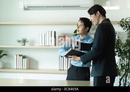 Client Consultation. Two businessmen discussing project details in a modern office. Stock Photo
