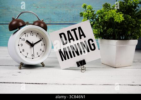 Data Mining text written on paper card with alarm clock on wooden background Stock Photo