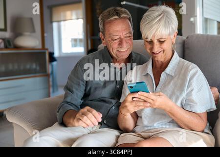 Happy senior couple using smartphone at home Stock Photo