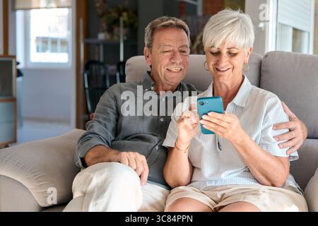 Happy senior couple using smartphone at home Stock Photo