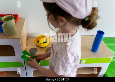 Preschooler Engaged in Imaginative Play with Toy Kitchen Set Stock Photo