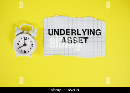 Underlying Asset text written on paper with alarm clock on yellow background Stock Photo
