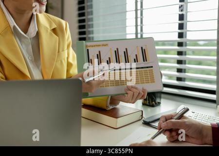 Two colleagues spend most of their time at workplace to meet deadlines, meeting between businessmen discussing first quarter sales, two employees work Stock Photo