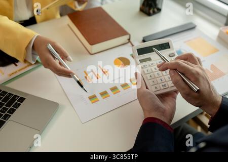 Two colleagues spend most of their time at workplace to meet deadlines, meeting between businessmen discussing first quarter sales, two employees work Stock Photo