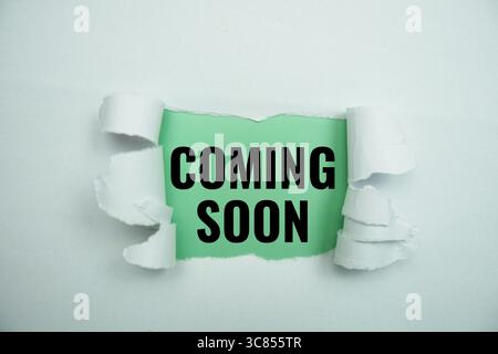 Coming soon message written on green paper with torn paper background Stock Photo