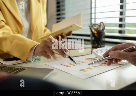 Two colleagues spend most of their time at workplace to meet deadlines, meeting between businessmen discussing first quarter sales, two employees work Stock Photo