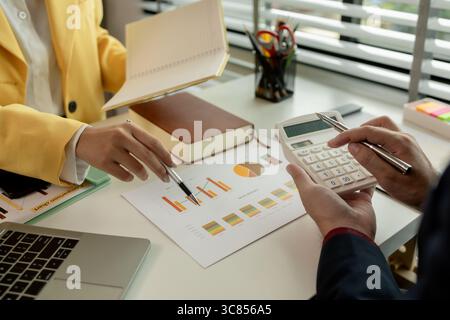 Two colleagues spend most of their time at workplace to meet deadlines, meeting between businessmen discussing first quarter sales, two employees work Stock Photo