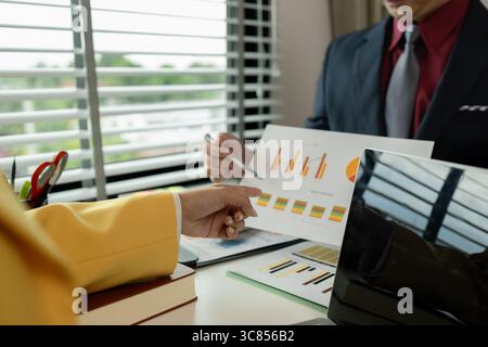 Two colleagues spend most of their time at workplace to meet deadlines, meeting between businessmen discussing first quarter sales, two employees work Stock Photo