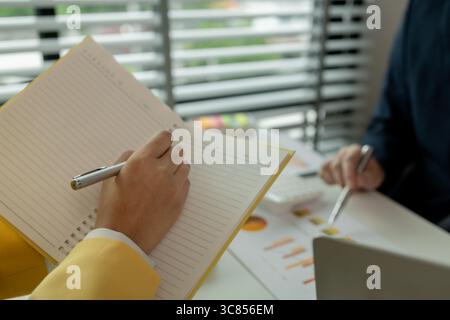 Two colleagues spend most of their time at workplace to meet deadlines, meeting between businessmen discussing first quarter sales, two employees work Stock Photo
