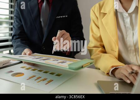 Two colleagues spend most of their time at workplace to meet deadlines, meeting between businessmen discussing first quarter sales, two employees work Stock Photo