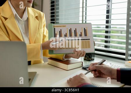 Two colleagues spend most of their time at workplace to meet deadlines, meeting between businessmen discussing first quarter sales, two employees work Stock Photo