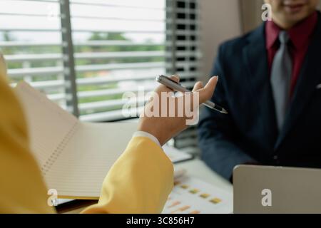 Two colleagues spend most of their time at workplace to meet deadlines, meeting between businessmen discussing first quarter sales, two employees work Stock Photo