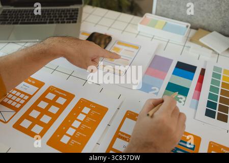 A web designer is using his idea to create a digital product design project that will meet the needs of users in terms of both appearance and feel whe Stock Photo
